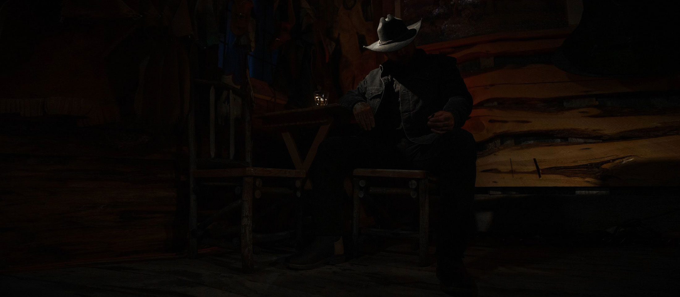 Cowboy sitting in a chair in the dark.